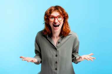 Kızıl saçlı ve turuncu gözlüklü genç kadın sevinç ve heyecanla kutluyor.