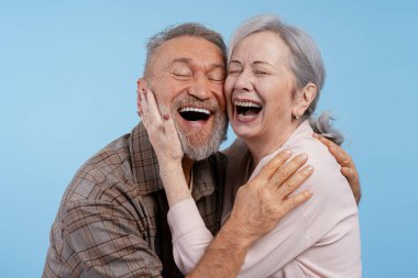 Yakın plan, mutlu, pozitif bir çiftin portresi, mavi arka planda kapalı gözleri olan gülümseyen kadın. İlişki kavramı