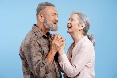 Romantik mutlu son sınıf çifti, yakışıklı bir adam ve güzel bir kadın mavi arka planda tek başlarına el ele tutuşuyorlar. Aşk, ilişki kavramı