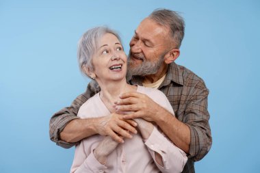 Mutlu, gülümseyen son sınıf çifti birbirlerine sarılıp mavi arka planda izole edilmiş pozlar veriyorlar. Aşk, ilişki kavramı