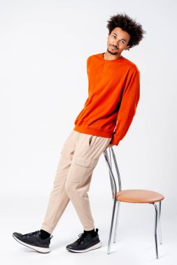 Turuncu kazaklı gülümseyen Afro-Amerikan bir adamın tüm vücut görüntüsü.