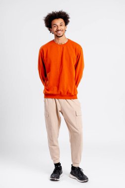 Genç adam ayakta, pozitif ışıldıyor ve stüdyo ortamında kendine güveni tam.