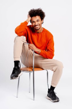 Genç Afro-Amerikan bir adam, günlük kıyafetleriyle poz veriyor, pozitif enerji yayıyor ve dostça bir ifade sergiliyor.