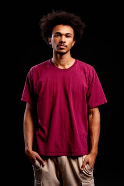 Afro saçlı, kendine güvenen genç adam stüdyo fotoğrafında gülümsüyor.