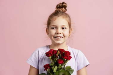 Kırmızı güller tutan, mutlu gülümseyen, anneliği ya da Sevgililer Günü 'nü kutlayan bir kız.