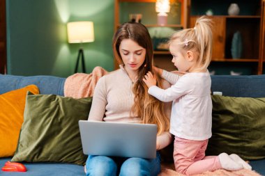 Anne evde dizüstü bilgisayarla uğraşırken, çocuk kanepesinde onunla oynuyordu.