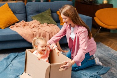 Anne ve kızı bir karton kutuyla oynuyorlar, çocukluk anlarının ve aile bağlarının tadını çıkarıyorlar.
