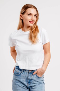 Beyaz t-shirt ve kot pantolon içinde poz veren genç bir kadın, gençliği ve sadeliği temsil ediyor.