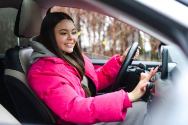 Pembe ceket giyen, modern araba kullanan ve GPS navigasyon sistemi kullanan güzel bir kadın. Ulaşım kavramı