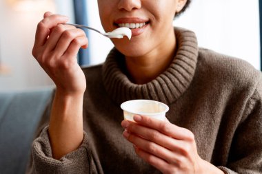 Kaşıkla yoğurt yiyen kadın sağlıklı bir yaşam tarzını ve sağlığını kucaklıyor.