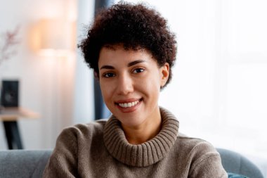 Kıvırcık saçlı, neşeli, çok kültürlü bir kadın. İçerde mutlu ve rahat.