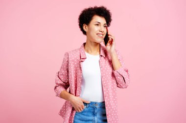 Mutlu gülümseyen Afrikalı Amerikalı kadın pembe arka planda izole bir şekilde telefona cevap veriyor. Çevrimiçi iletişim kavramı