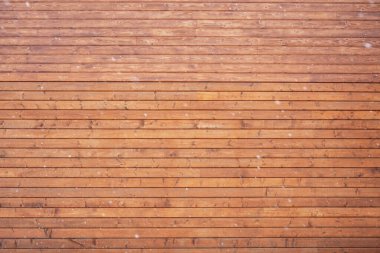 Kahverengi kereste yüzeyi, doğal desenli ve ince kar taneleri kış arkaplanı oluşturuyor.