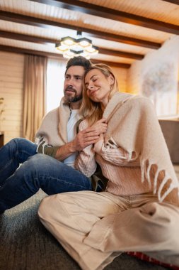 Happy couple cozying up under a blanket on the floor, finding comfort and intimacy in their home