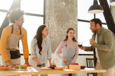 Gülümseyen mutlu çok uluslu arkadaşlar modern mutfakta pizza yapıp evde şarap içiyorlar. Arkadaşlık kavramı