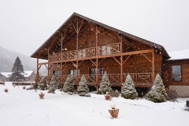 Kar yağan kırsal ahşap kulübe, kışlık bir dağ manzarasında rahat bir dinlenme sunuyor.