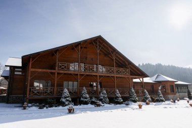 Büyük bir kereste oteli ya da tatil köyü karlı bir ortamda sıcak bir kış tatili hissi yaratıyor.