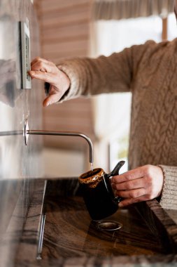 Siyah bir bardağı şeker kutusundan çıkan tatlı suyla dolduran kişi.
