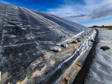 View of the installation process of geosynthetics with geomembrane on mine fill slopes and benches