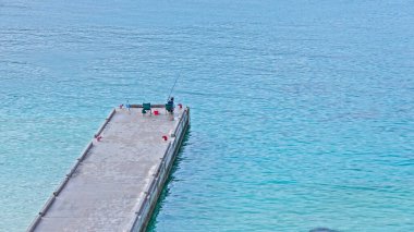 Çok temiz, açık mavi suyu olan bir körfeze bakan iskele manzarası