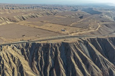 Çöl uçurumlarının ve kurak manzaraların kenarına inşa edilmiş bir otoyol manzarası.