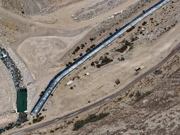 Yeraltı su taşımacılığı için maden kenarlarındaki jeosentetik ve kaya kanallarının havadan görünüşü