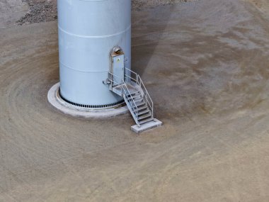 Girişinde çelik merdiven olan devasa bir rüzgar türbininin temeli ve temeli görünüyor..