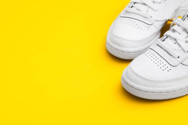 Sarı arka planda bir çift şık beyaz spor ayakkabısı. Yaşam tarzı spor ayakkabısı. Uzayı kopyala Mesaj için yer var. Stüdyo fotoğrafı