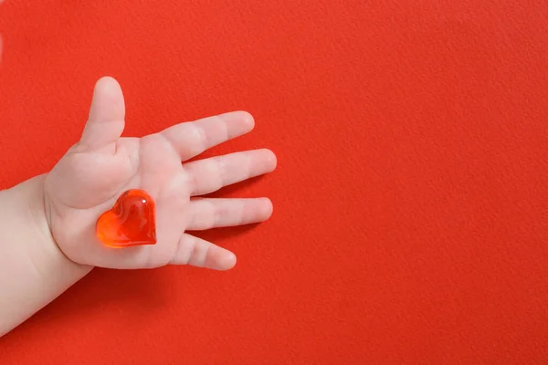 Corazón Rojo Mano Del Bebé Recién Nacido Sobre Fondo Rojo — Foto de Stock