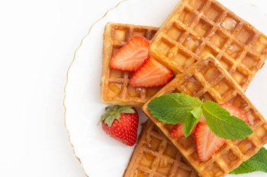 Breakfast with belgium waffles with strawberry, mint on plate and orange juice