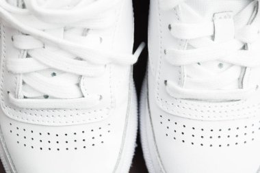 Yakından bir çift şık beyaz spor ayakkabısı görünüyor.