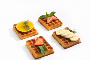 Belgium waffles with strawberry, banana and orange with syrup on white