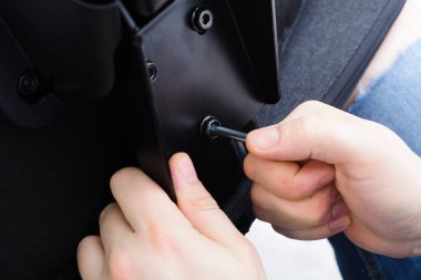 Kafkasyalı erkek elleri sandalyeyi arkadan vidaladı. Ofis sandalyesini içeride monte ediyorum. 12. Adım