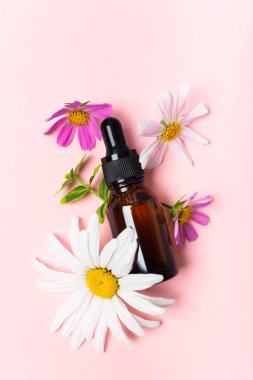 Kozmetik yağı, parfüm ya da kahverengi bardakta pipetli ve çiçekli ilaç.