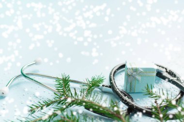 Steteskop, hediye kutusu ve mavi üzerine noel ağacı olan Noel tıbbi konsepti.