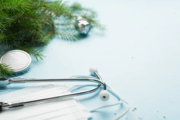 Steteskop, hediye kutusu ve mavi üzerine noel ağacı olan Noel tıbbi konsepti.