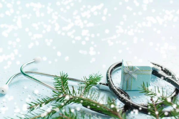 Steteskop, hediye kutusu ve mavi üzerine noel ağacı olan Noel tıbbi konsepti.