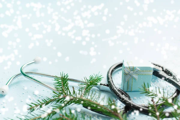 Concetto medico natalizio con stetoscopio, confezione regalo e albero di Natale su blu Immagini Stock Royalty Free
