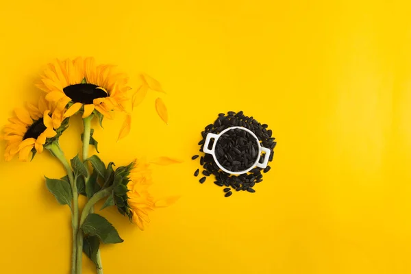 Подсолнухи и семечки подсолнечника в белой керамической чаше на желтом фоне Стоковое Изображение