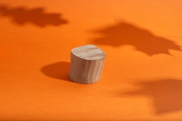 Podio in legno vuoto con forma circolare in piedi su arancio con ombra di foglie — Foto Stock