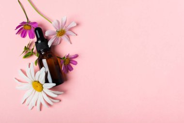 Kozmetik yağı, parfüm ya da kahverengi bardakta pipetli ve çiçekli ilaç.
