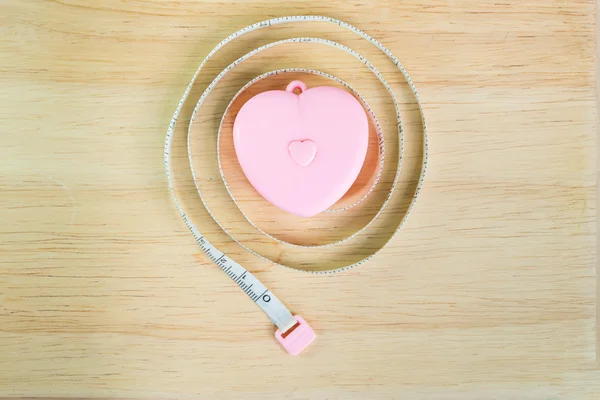 ピンクのハートの木製の背景に測定テープ — ストック写真