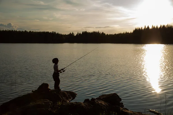 Child on an evening fishing trip. Sunset.