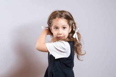 Kız elinde okul çantasıyla kameraya bakıyor.