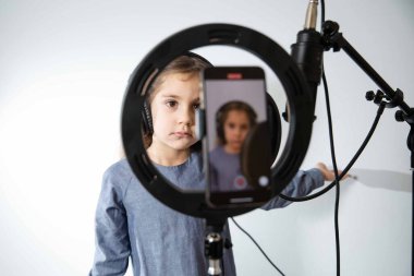 Kız blogcu canlı yayın yapıyor. Kız mikrofona şarkı söylüyor. Kulaklık takıyor.