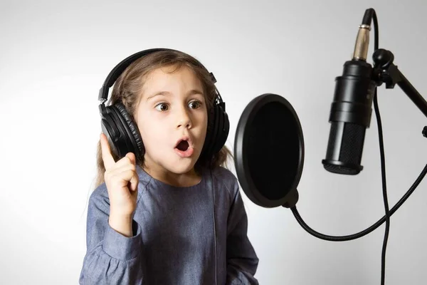 The girl is singing a song into the microphone and looking at the camera — Stock Photo, Image
