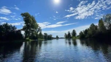 Zaman aşımı. Yüzen bir tekneden ateş etmek. Güneş ışığı. Hızlı nehir ve bulutlar. Nehrin üzerinde bulutlar olan bir manzara. Dışarıda..
