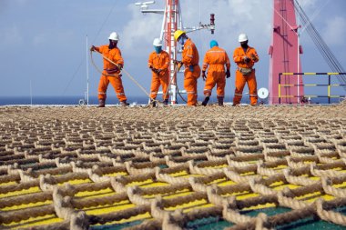 Offshore işçileri petrol sahasında bir inşaat mavnasına helikopter ağı kuruyor.