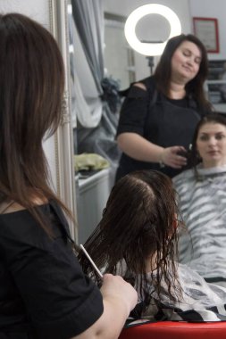 Küçük kuaförde müşterisiyle çalışan kuaför. Kuaför ve müşteri saç tıraşı seçiyor..