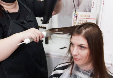 Küçük kuaförde müşterisiyle çalışan kuaför. Kuaför ve müşteri saç tıraşı seçiyor..